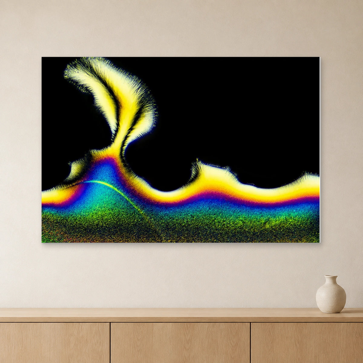 Vitamin C als Mikrokristall-Wandbild auf Alu-Dibond: Gelb-blaue Kristallstruktur auf schwarzem Grund an heller Wand über einem Sideboard aus Eichenholz (Raum-Mockup).