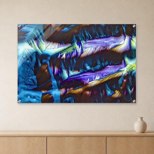 Paracetamol als Mikrokristall-Wandbild auf Acrylglas: Blaue und violette, längliche Kristallstrukturen an heller Wand über einem Sideboard aus Eichenholz (Raum-Mockup).