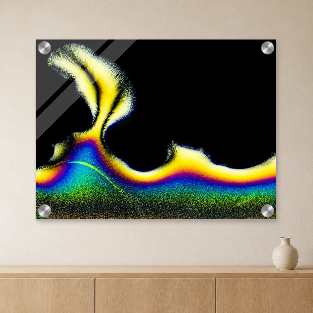 Vitamin C als Mikrokristall-Wandbild auf Acrylglas: Gelb-blaue Kristallstruktur auf schwarzem Grund an heller Wand über einem Sideboard aus Eichenholz (Raum-Mockup).