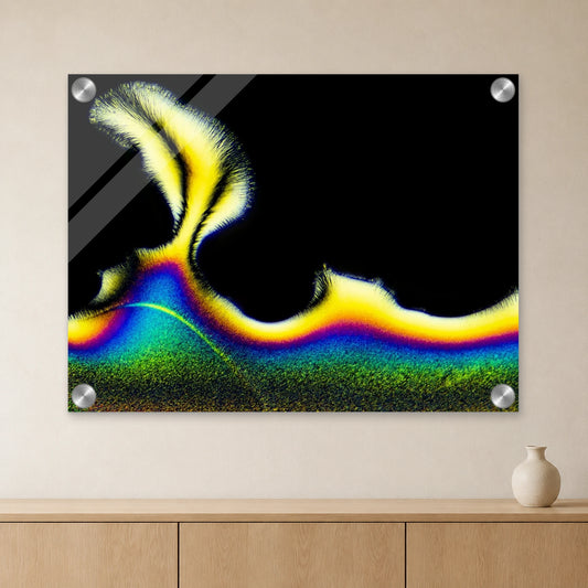 Vitamin C als Mikrokristall-Wandbild auf Acrylglas: Gelb-blaue Kristallstruktur auf schwarzem Grund an heller Wand über einem Sideboard aus Eichenholz (Raum-Mockup).